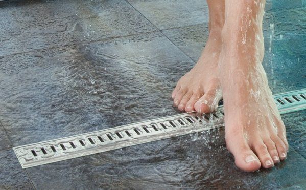 A person is standing in a shower with their feet in the water.