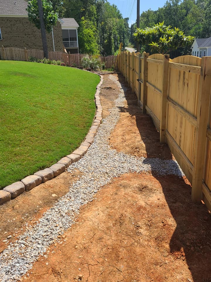 A wooden fence is surrounded by gravel and grass.
