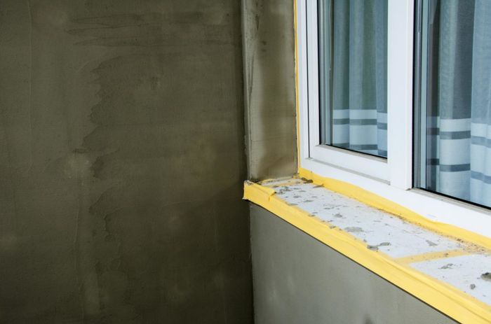 A window sill is being installed in a room with a concrete wall.