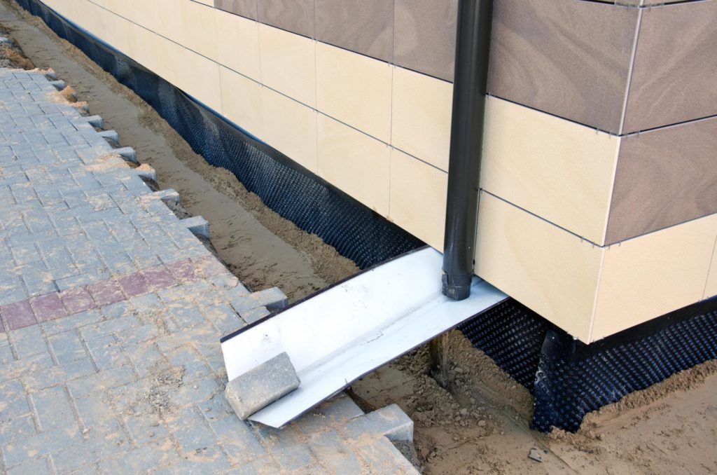 A drain pipe is being installed on the side of a building.