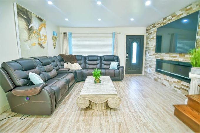 Modern living room with gray sectional sofas, marble coffee table, tiled floor, and large wall mirror