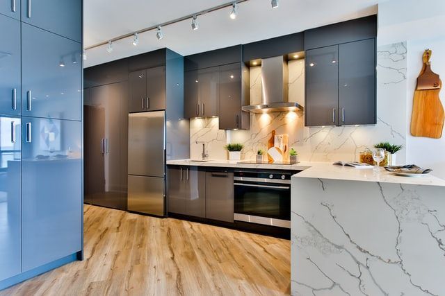 Modern kitchen with blue cabinets, marble island, wood floors, and stainless steel appliances