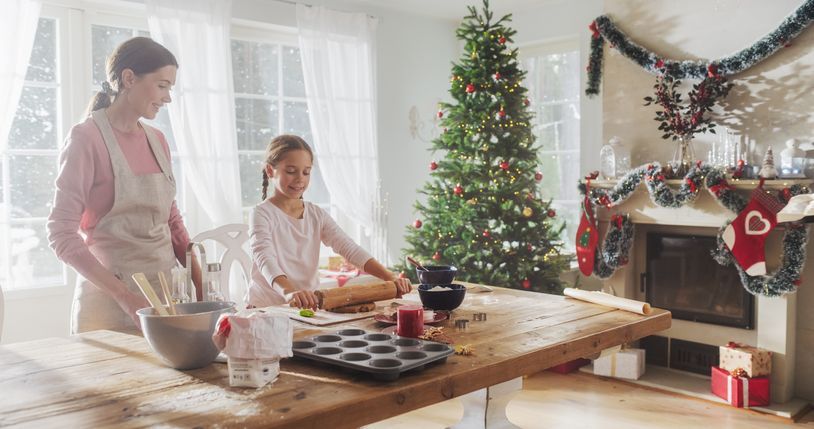 a woman and child are preparing christmas cookies in front of a christmas tree