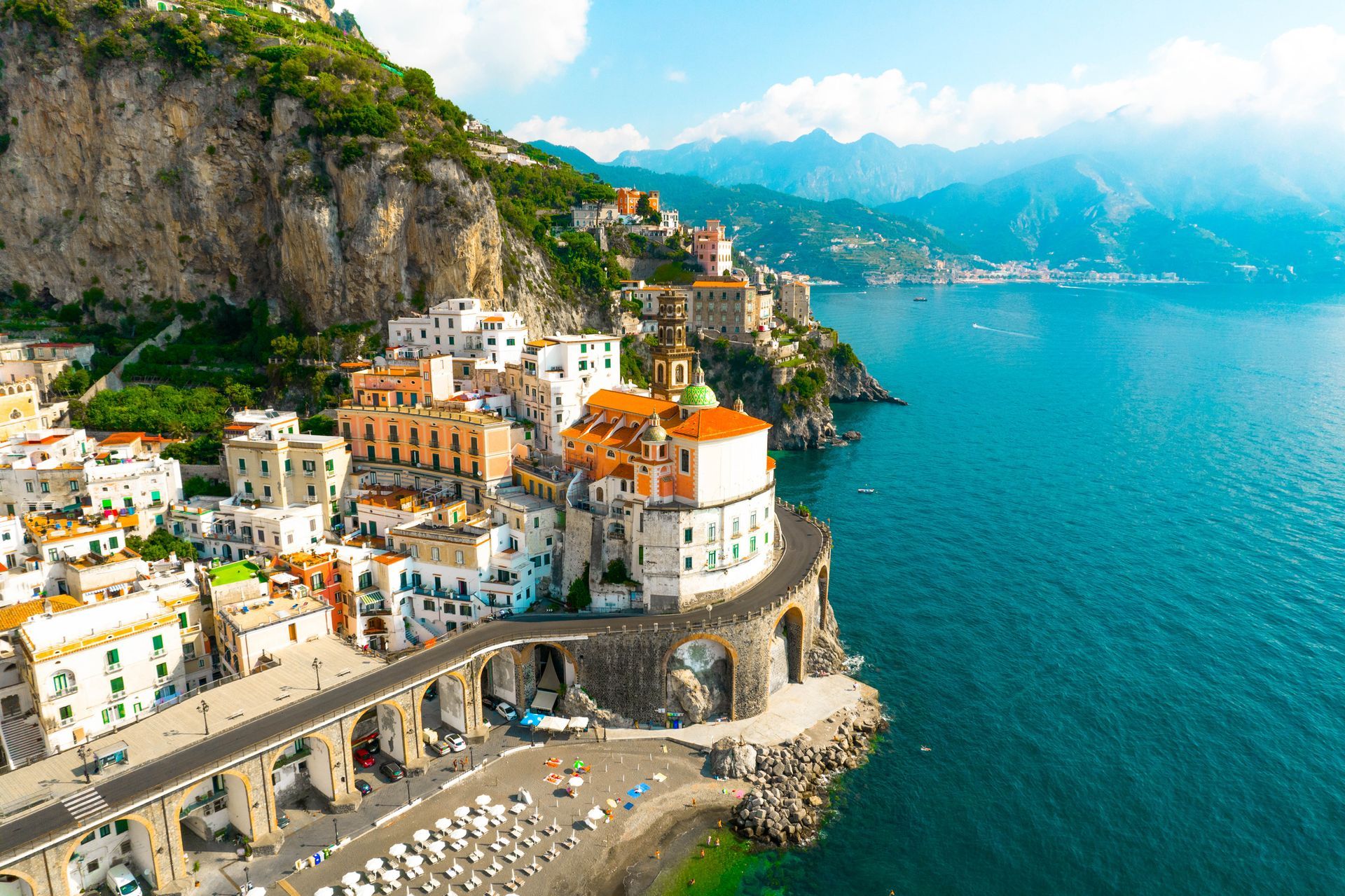 An aerial view of a small town on a cliff overlooking the ocean.
