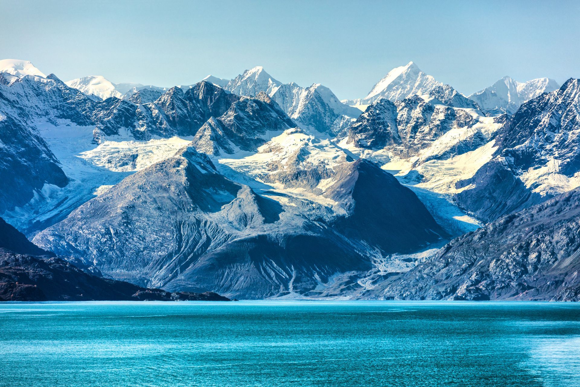 A large body of water surrounded by snow covered mountains.