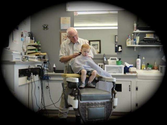 Barber giving a young boy a haircut in a small shop.