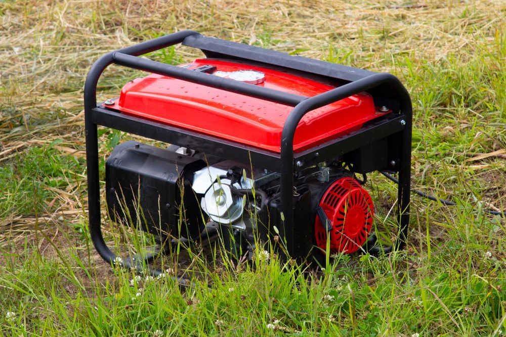 Red-and-black Portable Generator Sitting in Tall Grass Outdoors — PowerMaster Batteries Moree in St, Moree, NSW