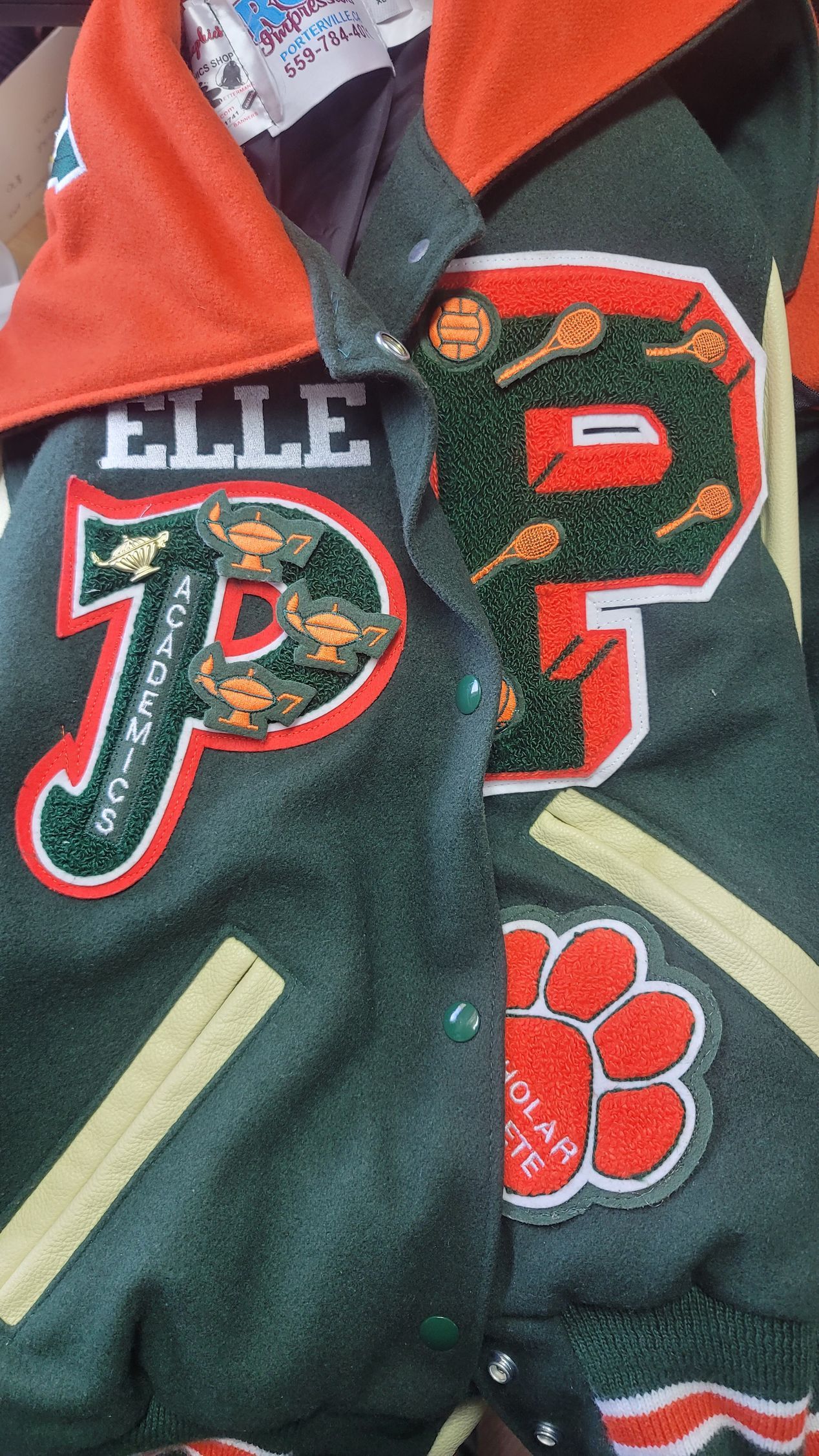 Deep green marching band jacket with gold treble clef patch and BAND lettering