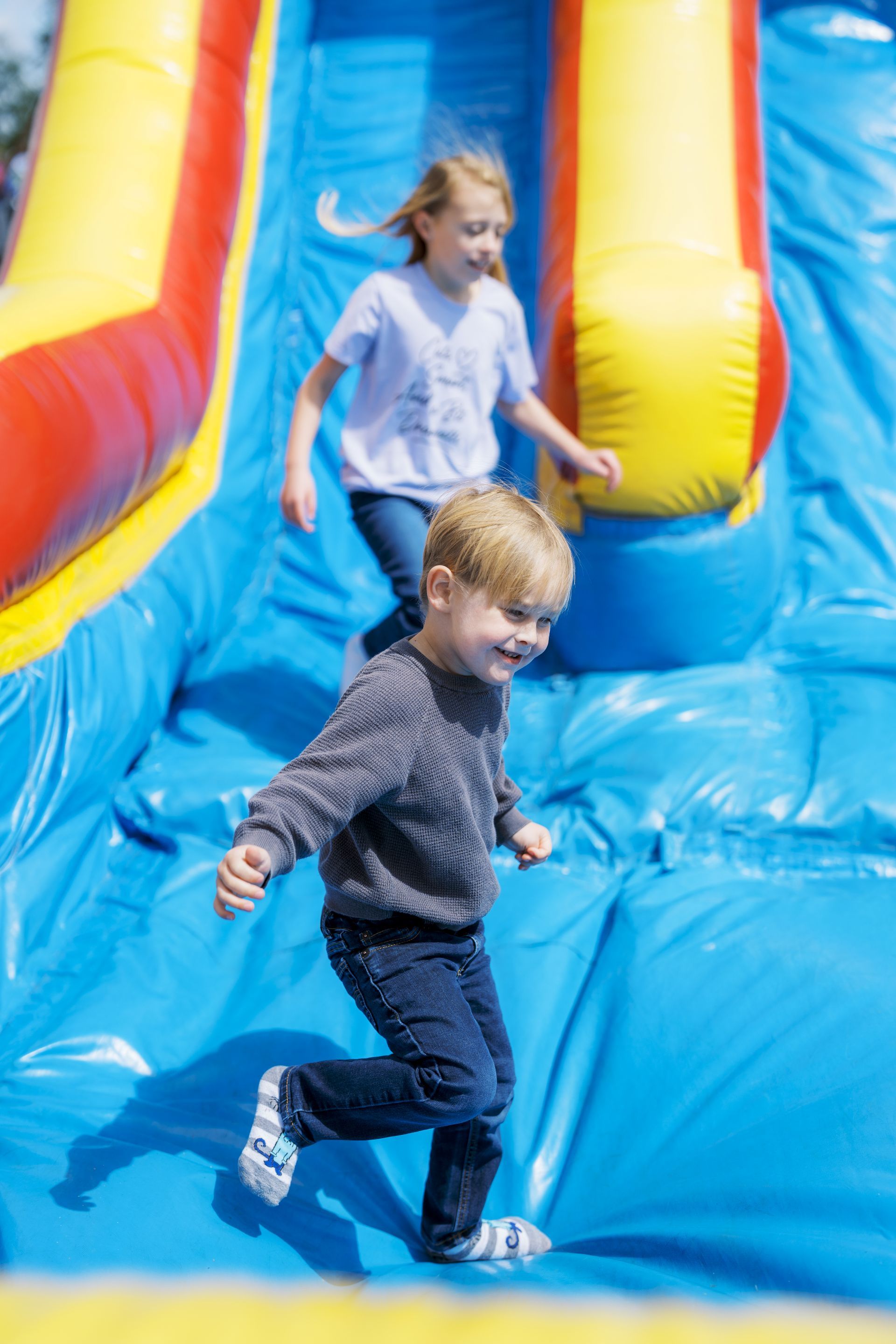 Two children running on a colorful inflatable bounce slide