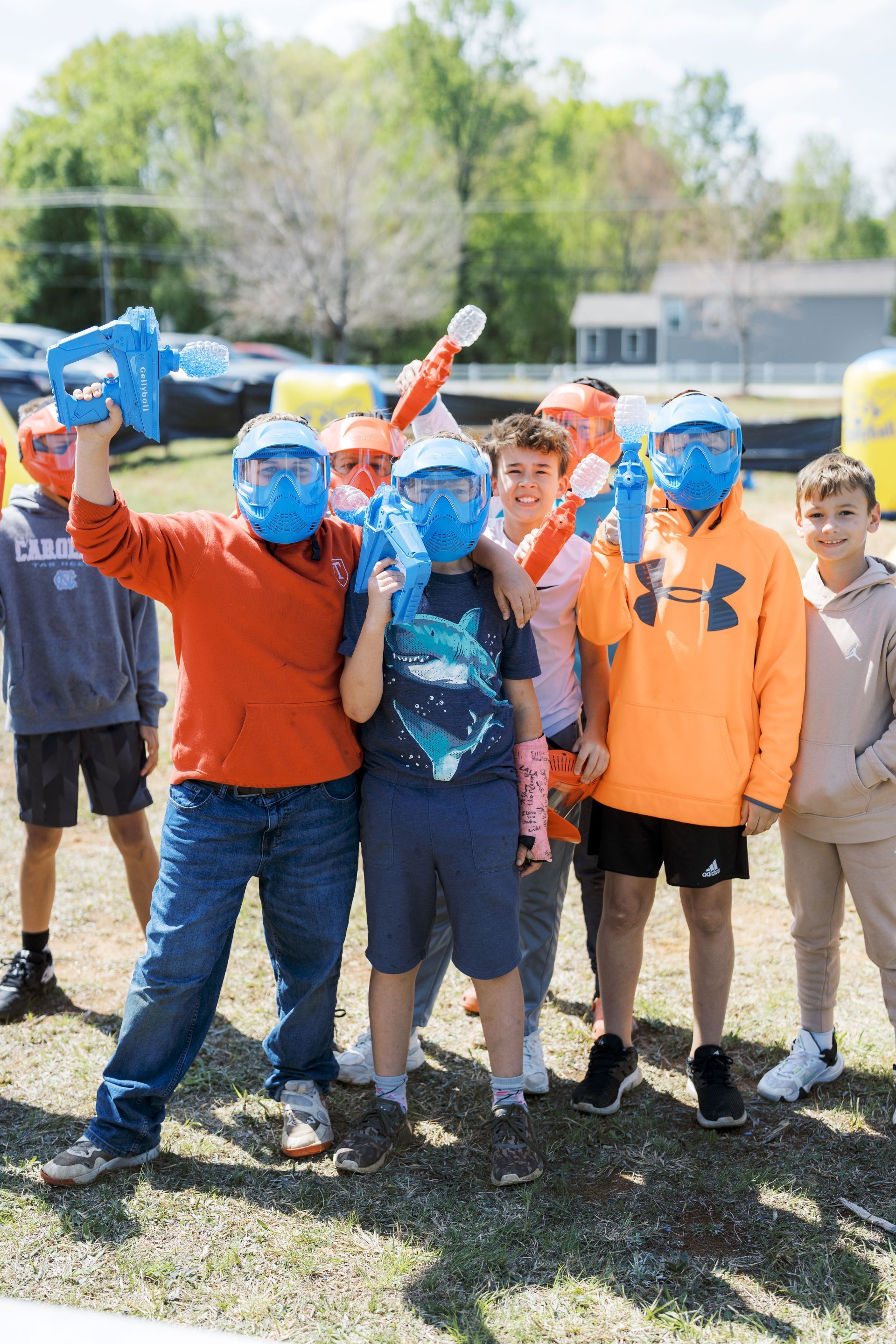 Group of kids outdoors, smiling with blue face paint and raised fists on a sunny field.