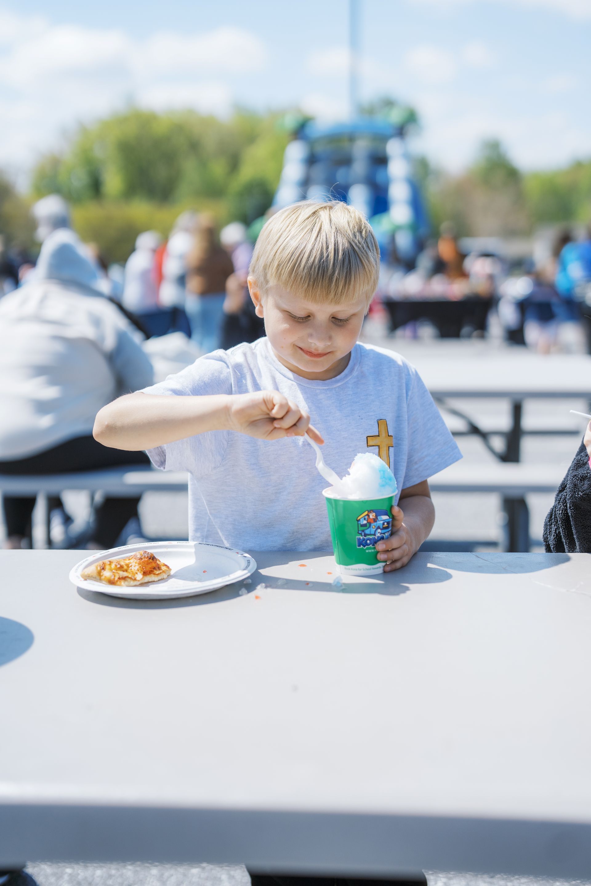 Child eating ice cream at an outdoor picnic table on a sunny day