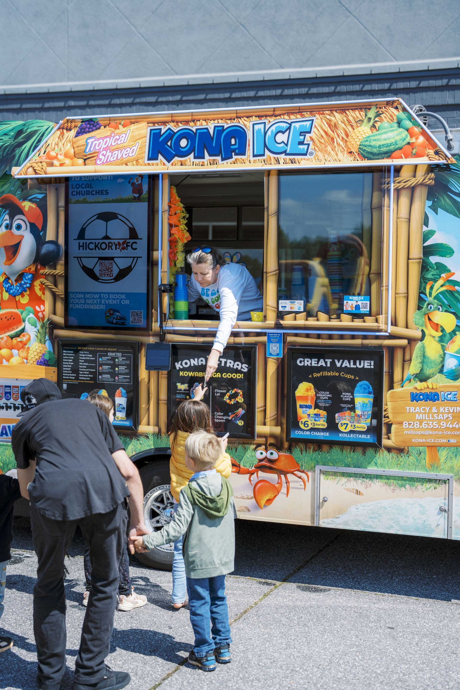 Kona Ice truck serving shaved ice to children at a roadside stand