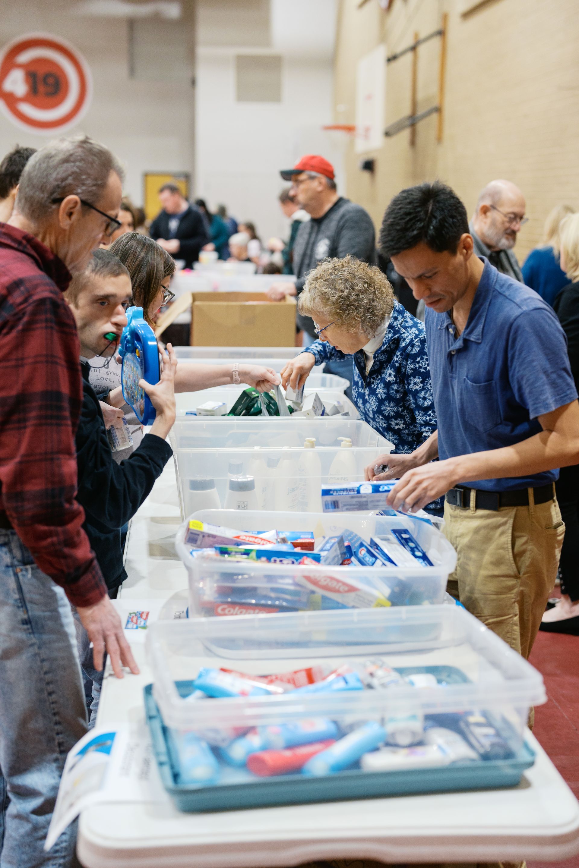 People sorting donated supplies at a community event table with clear plastic bins