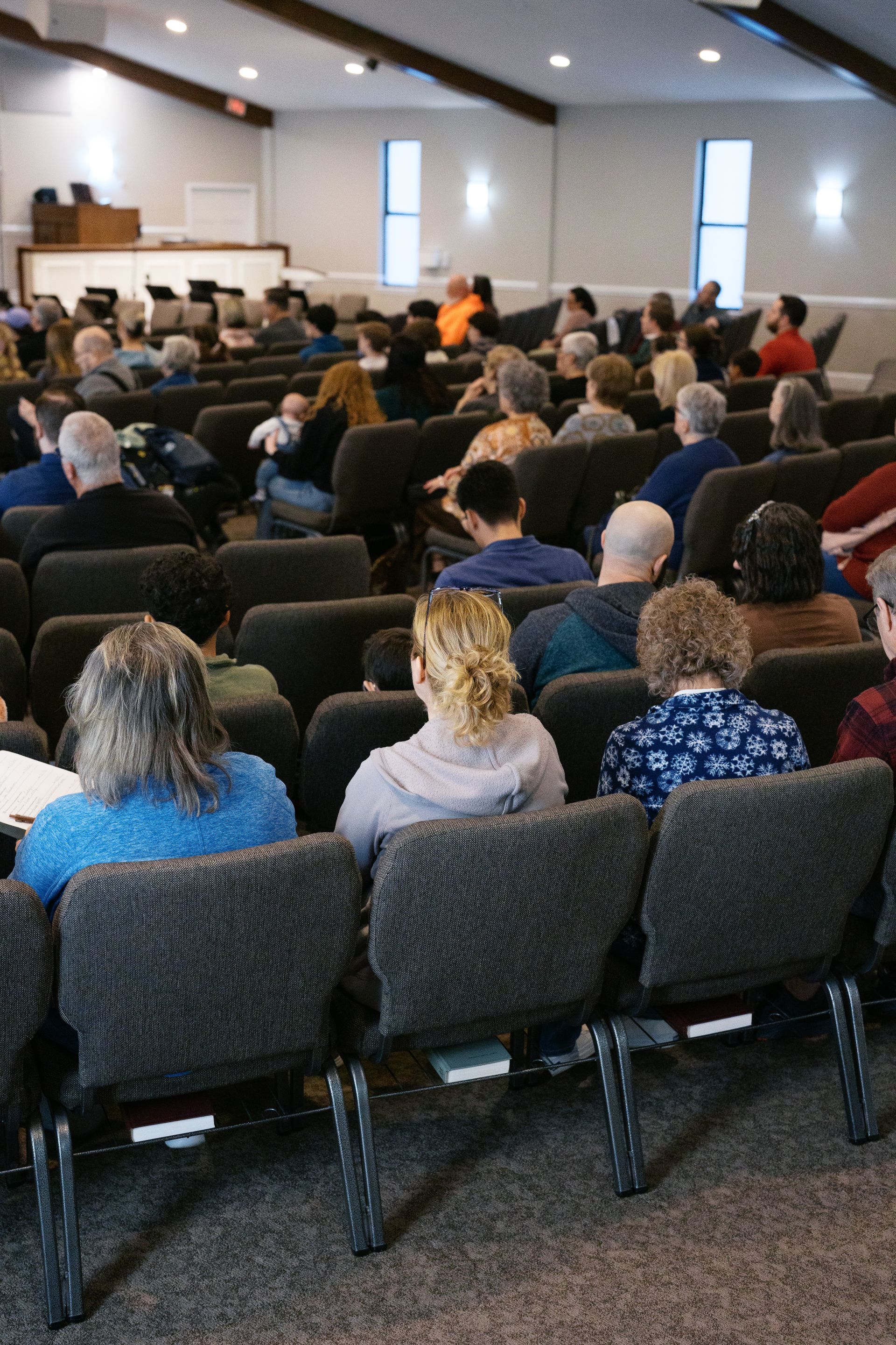 Audience seated in a church or lecture hall, facing the front stage during a presentation