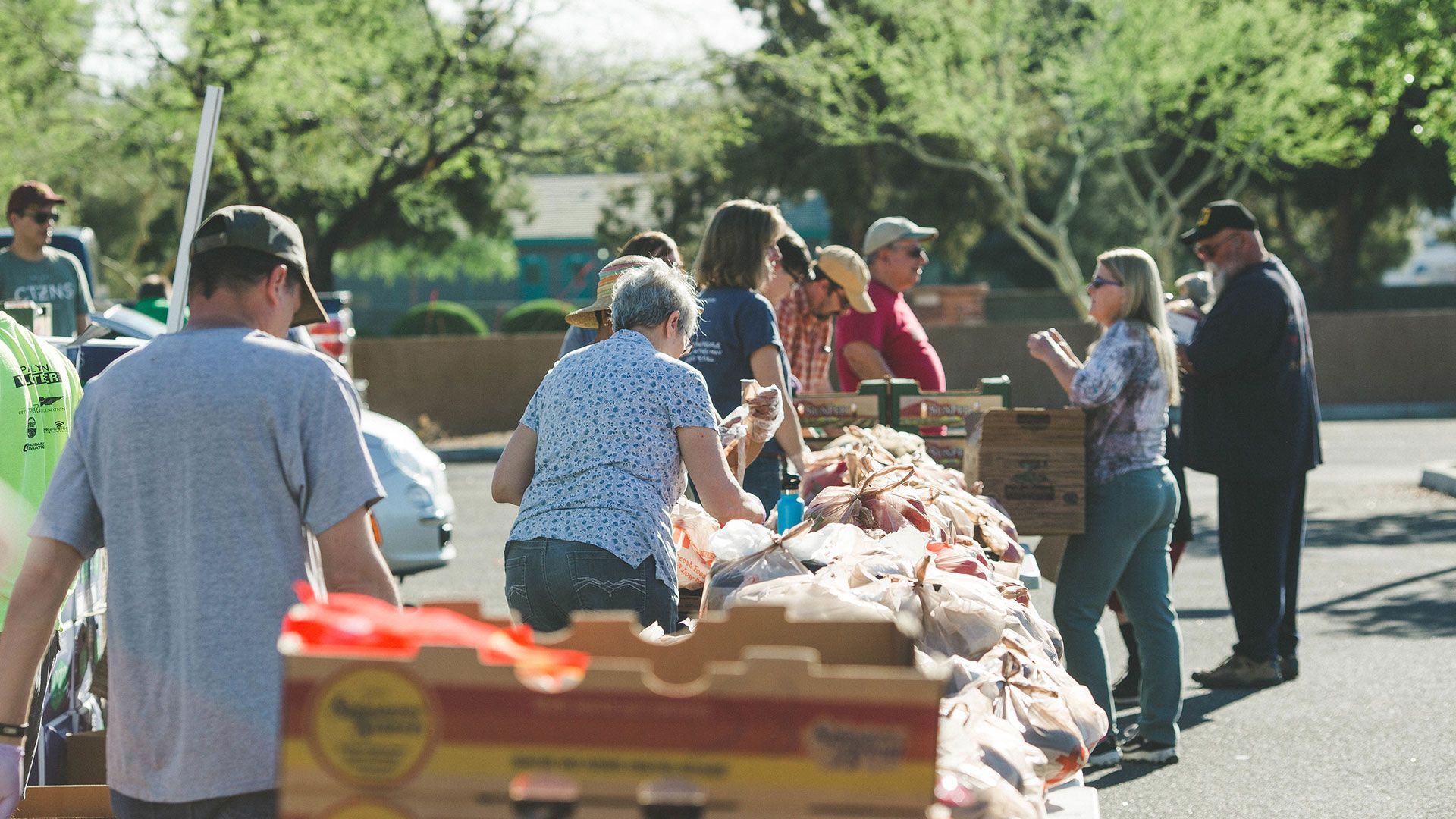 People sorting donated food at outdoor tables on a sunny day
