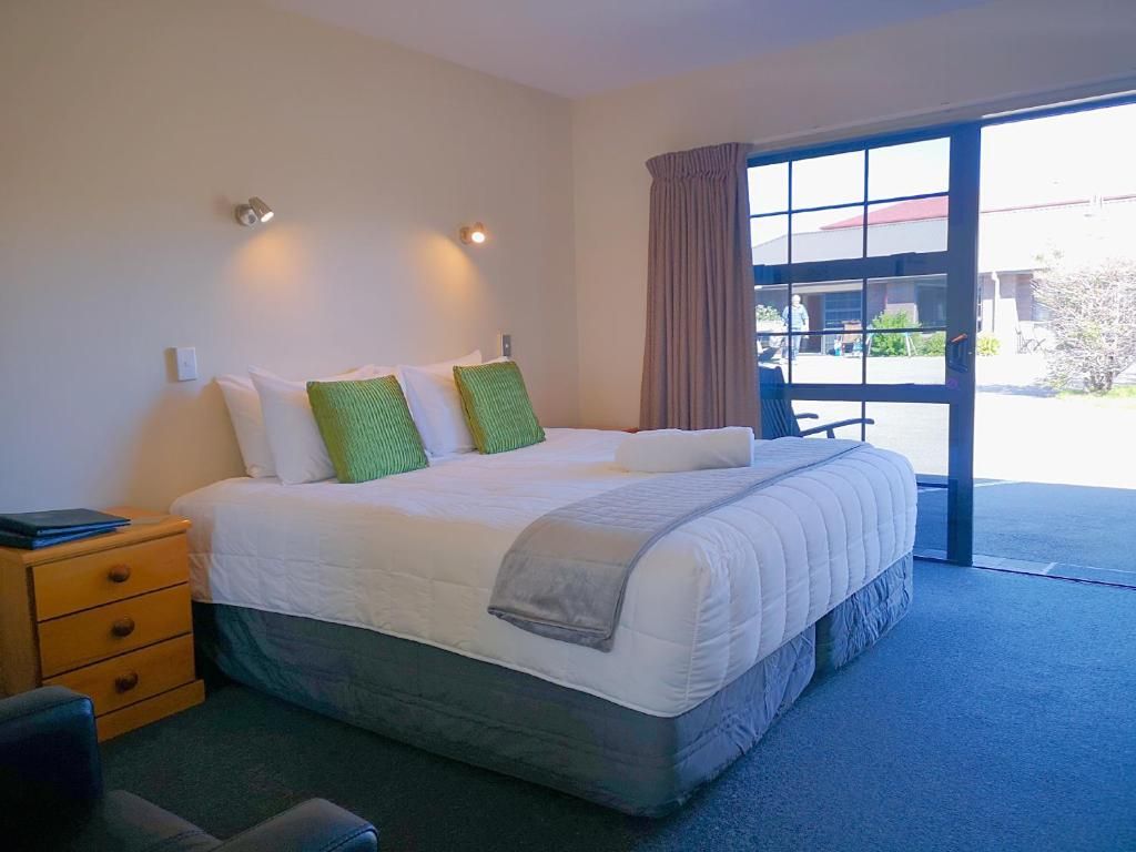 A hotel room with a large bed and a sliding glass door.