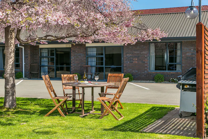 There is a table and chairs in the grass in front of a brick building.