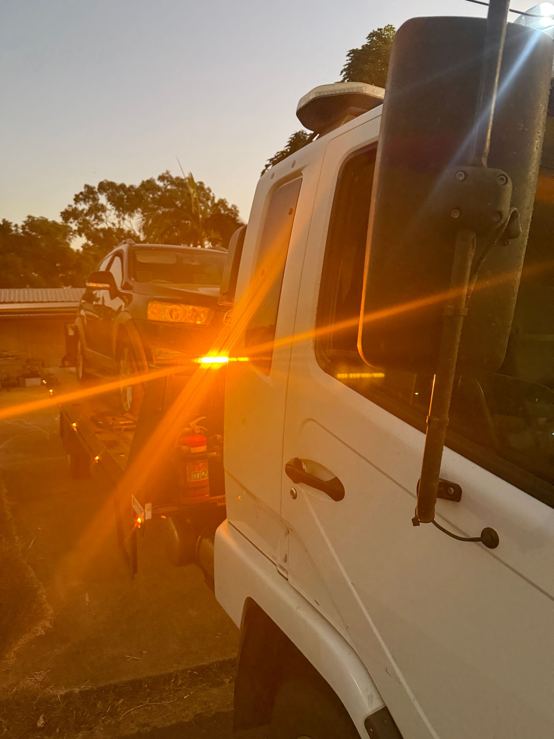 A Tow Truck Is Towing A Car On The Road At Night — Rockhampton Towing And Transport in Emerald, QLD