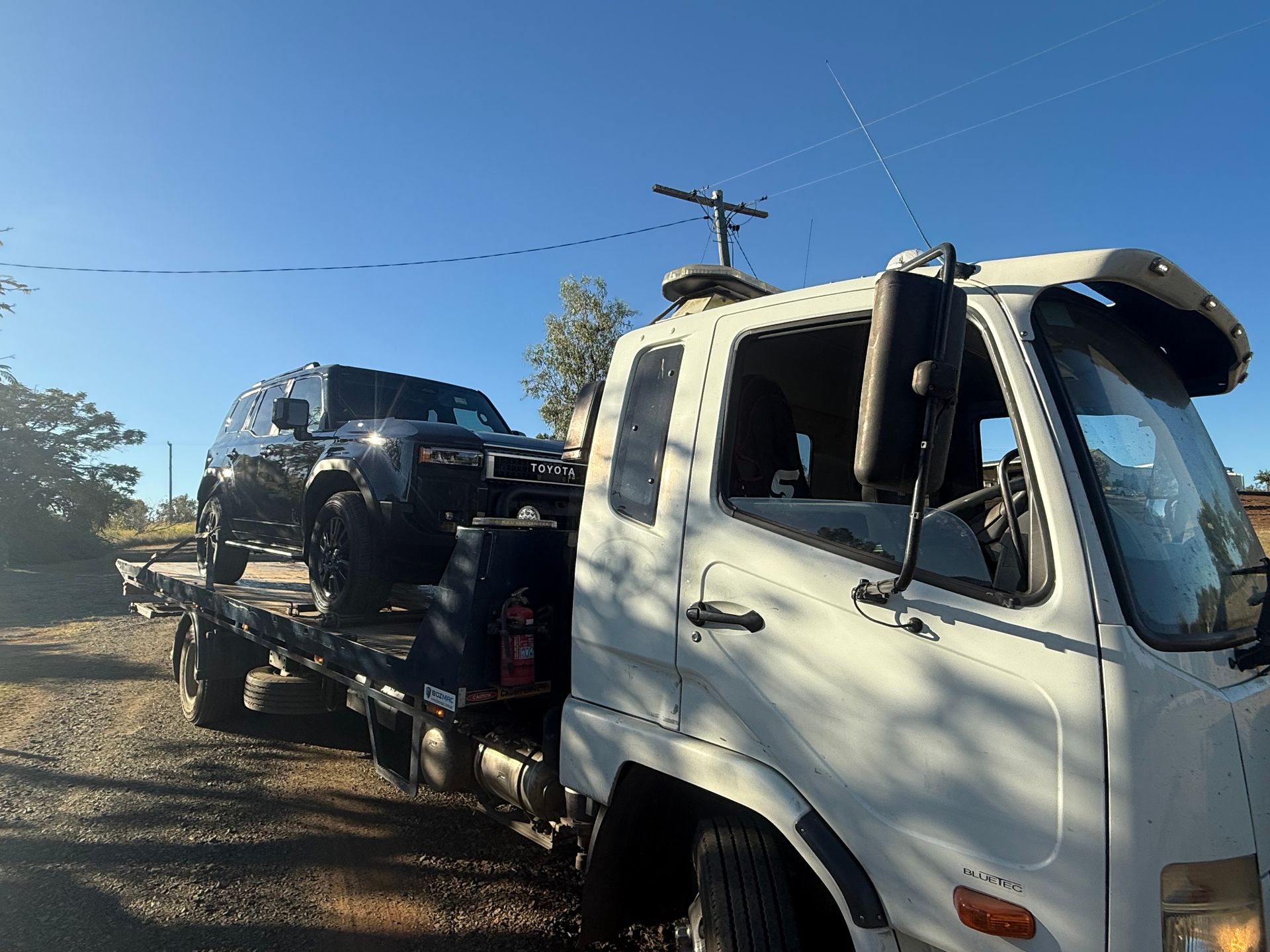 A Tow Truck Is Towing A Car On A City Street — Rockhampton Towing And Transport in Emerald, QLD