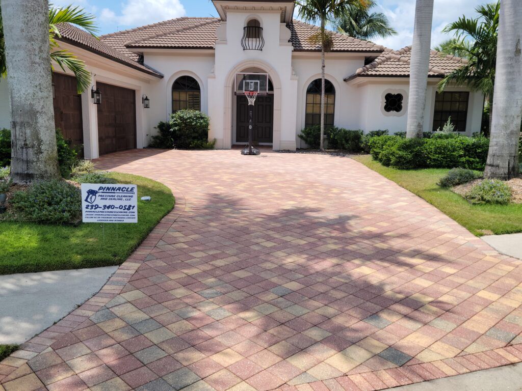 A multi-colored brick driveway leading to a white house