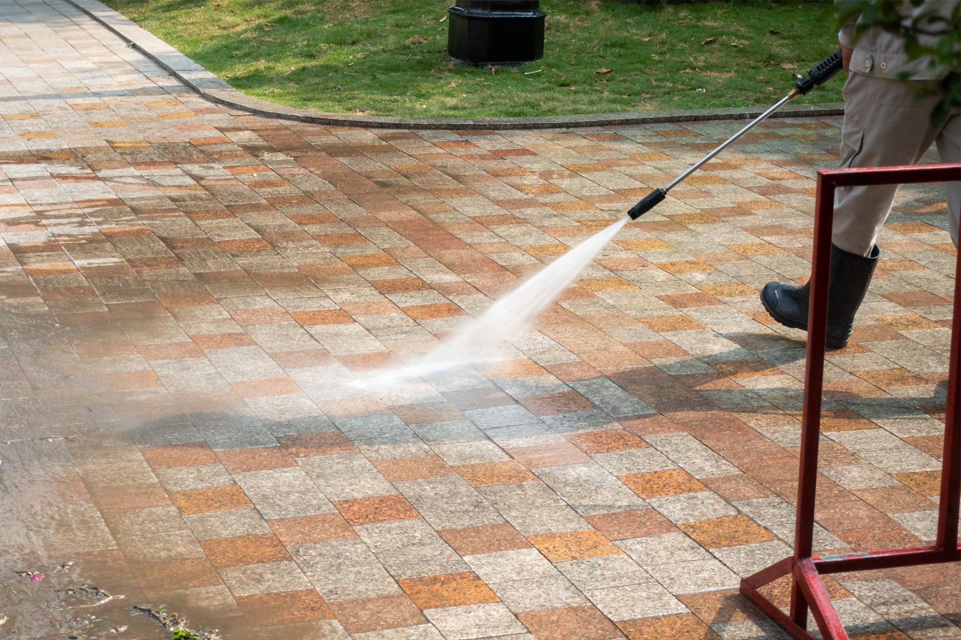 Person power washing brick pavers, outdoors.