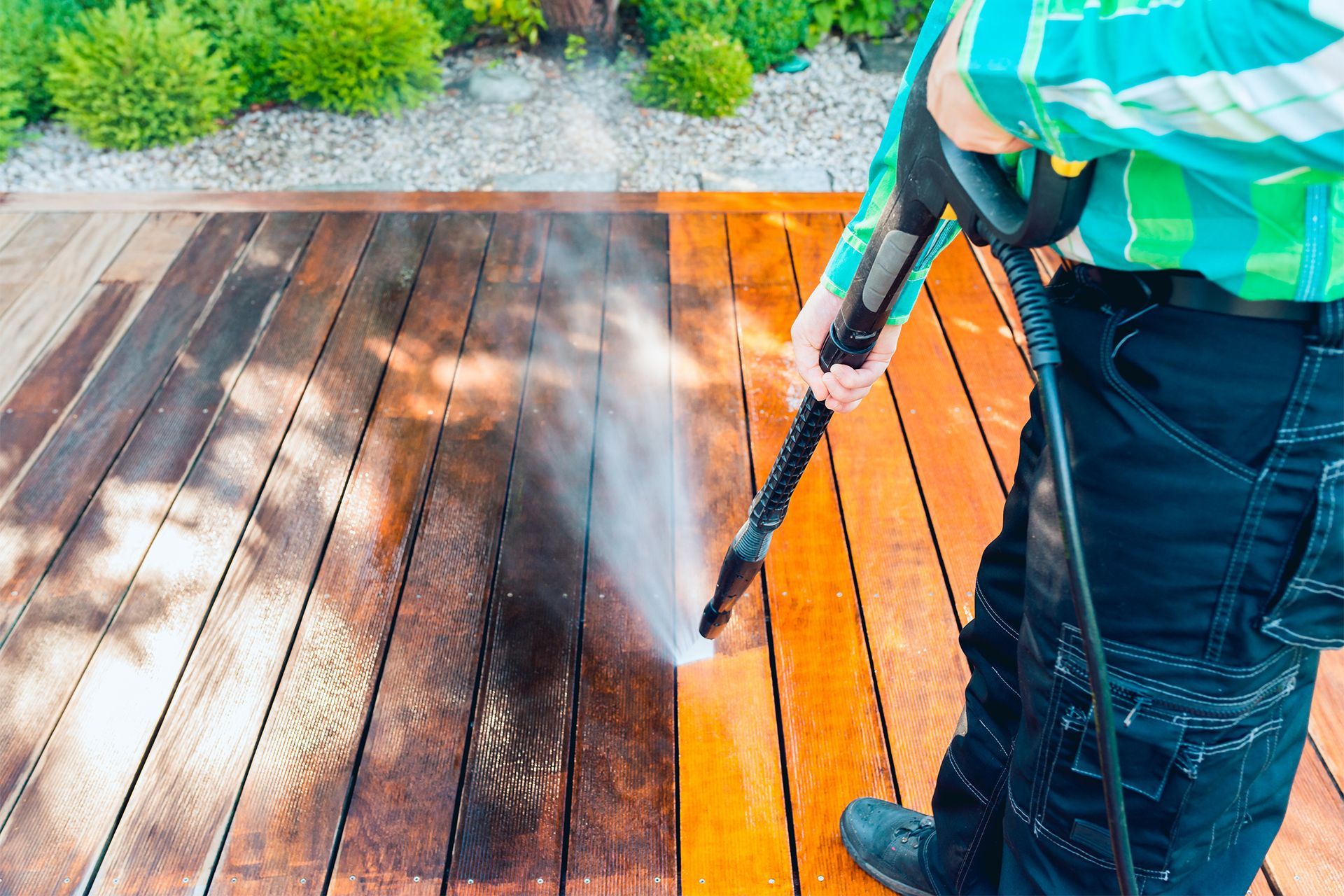 Person power washing a wooden deck. Person power washing a wooden deck.