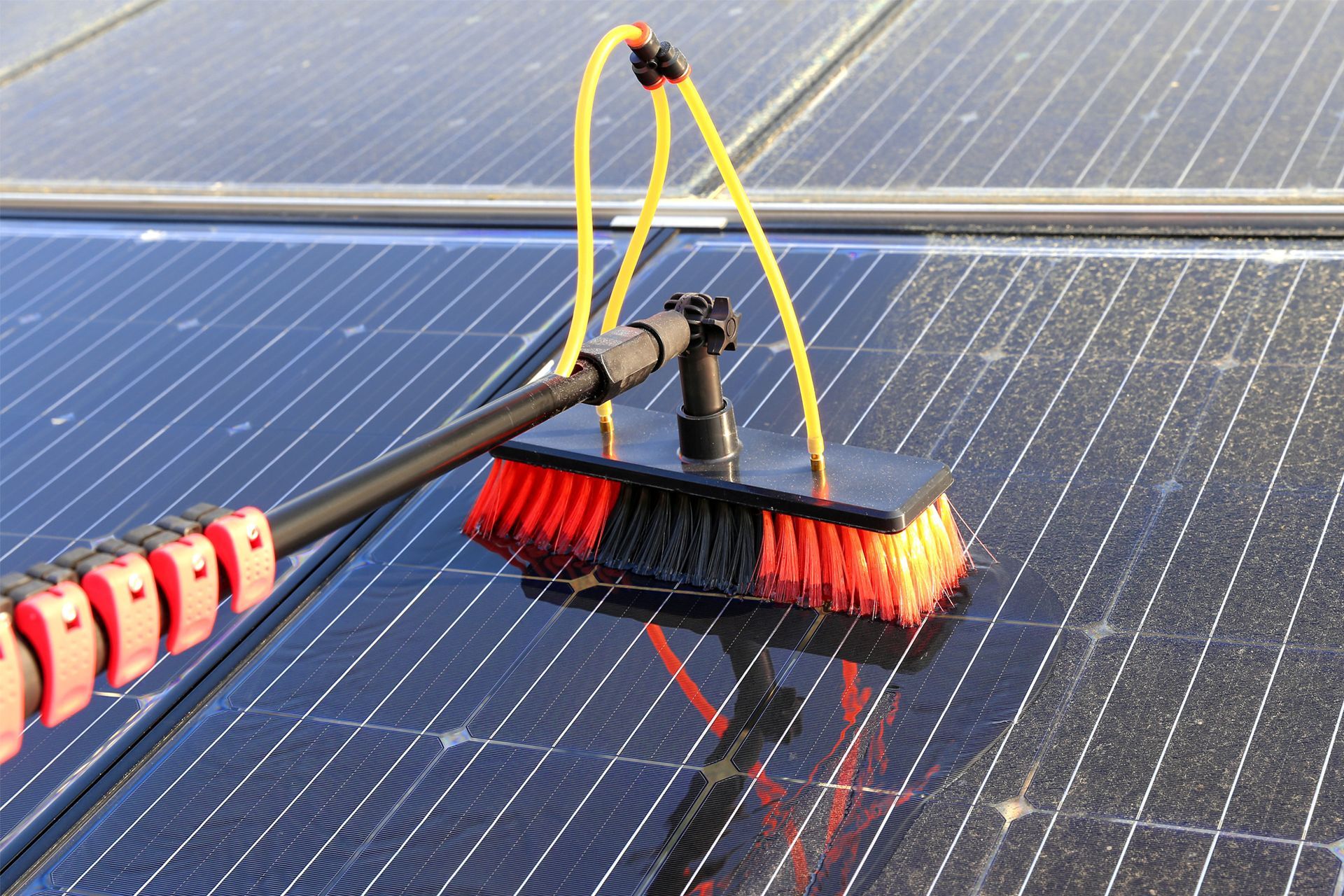 Brush cleaning solar panels on a rooftop. Brush cleaning solar panels on a rooftop.