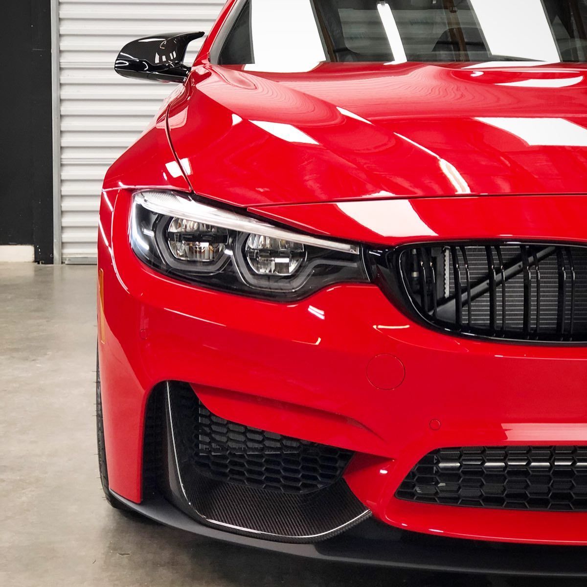 A red car is parked in front of a garage door