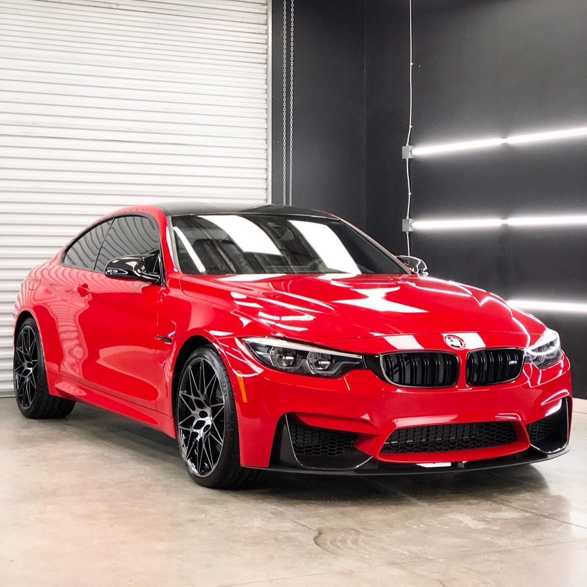 A red bmw m4 is parked in a garage.