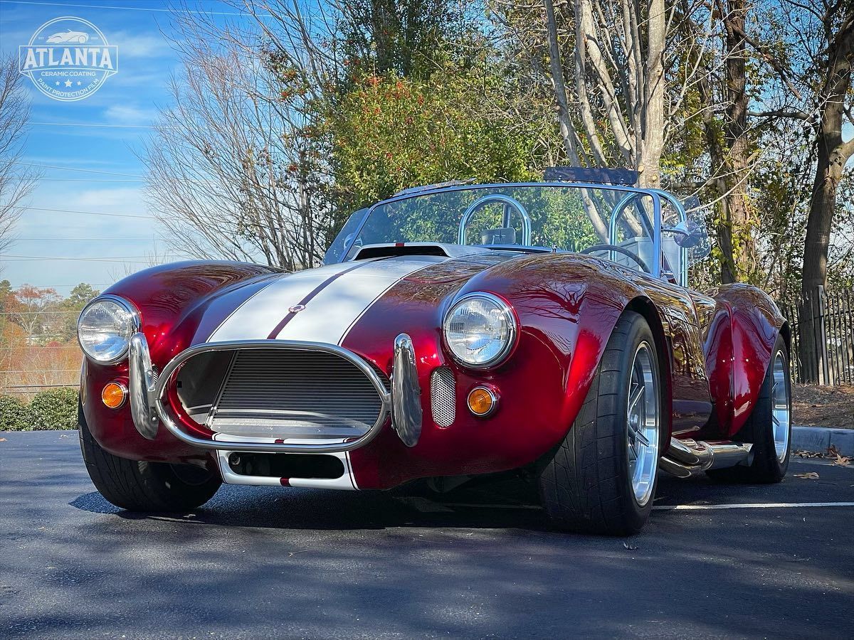 A red and white sports car is parked on the side of the road.