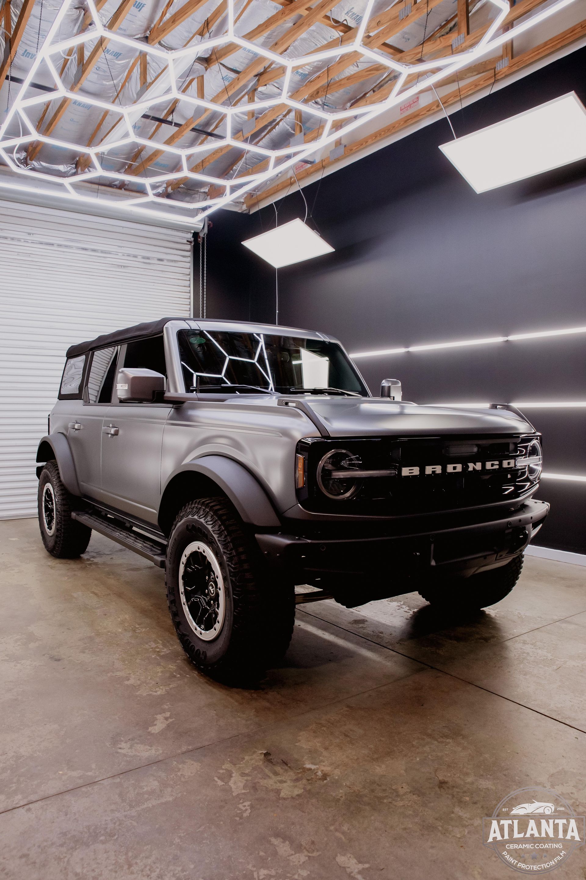 Gray Ford Bronco SUV parked in a garage with hexagonal and rectangular lights.
