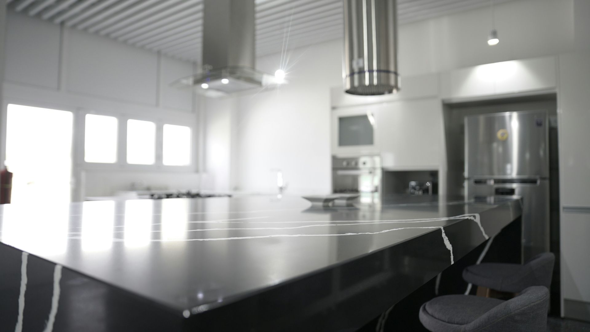 A kitchen with a black counter top and a stainless steel refrigerator