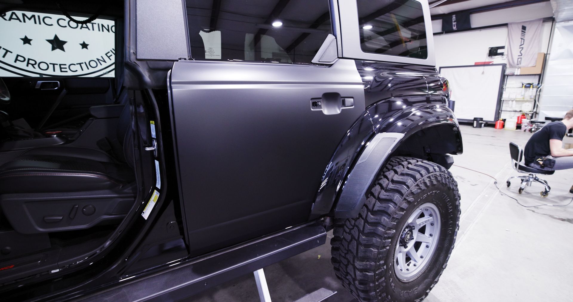 A black jeep is parked in a garage with the door open.