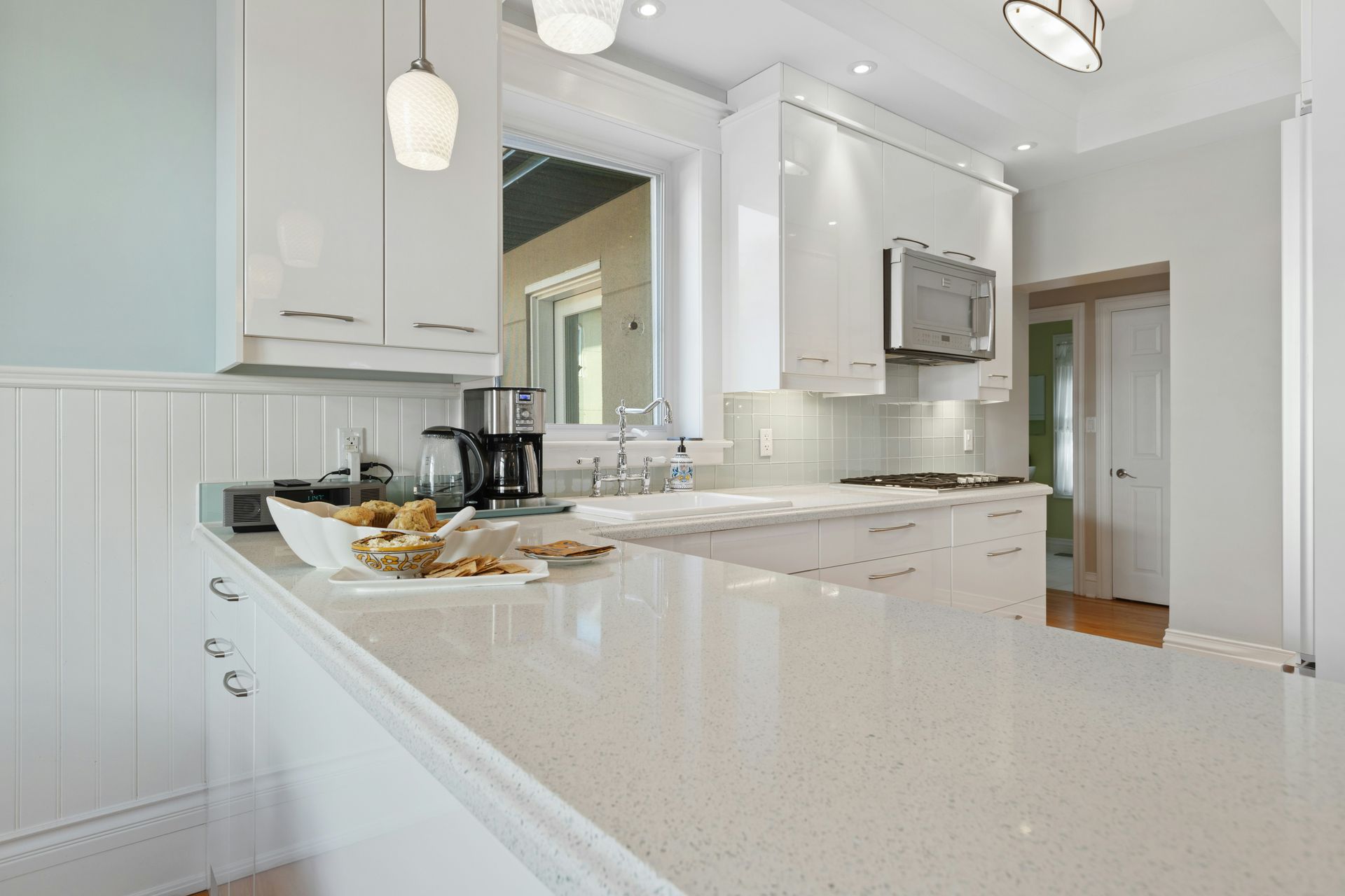 A kitchen with white cabinets , a microwave , a sink , and a counter.