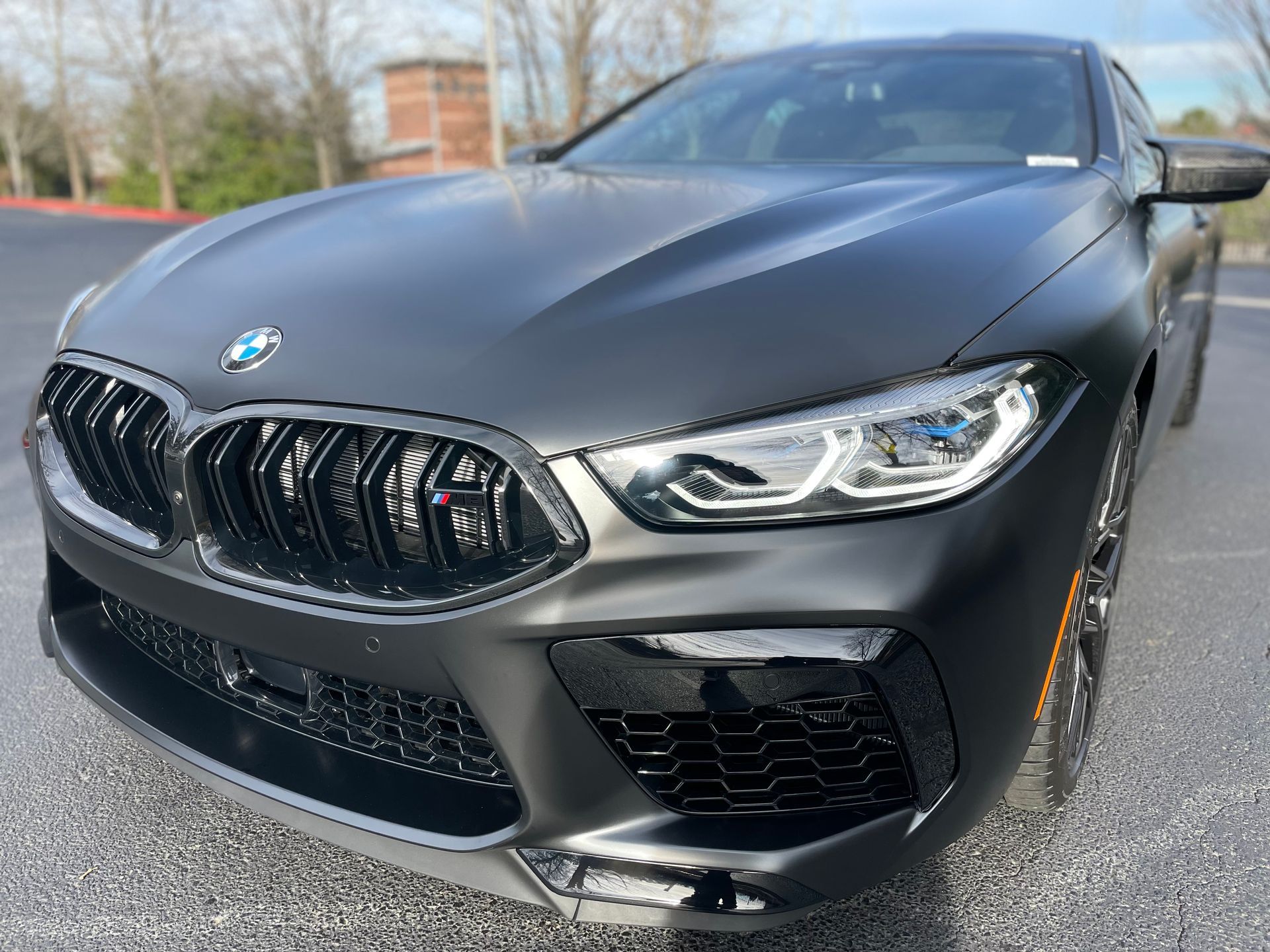 A black bmw m8 is parked in a parking lot.