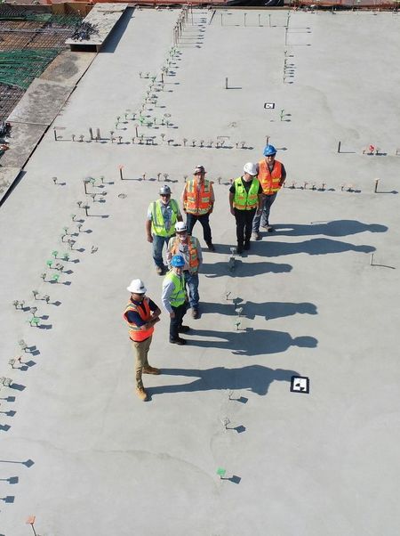 A group of construction workers are walking on a concrete roof.