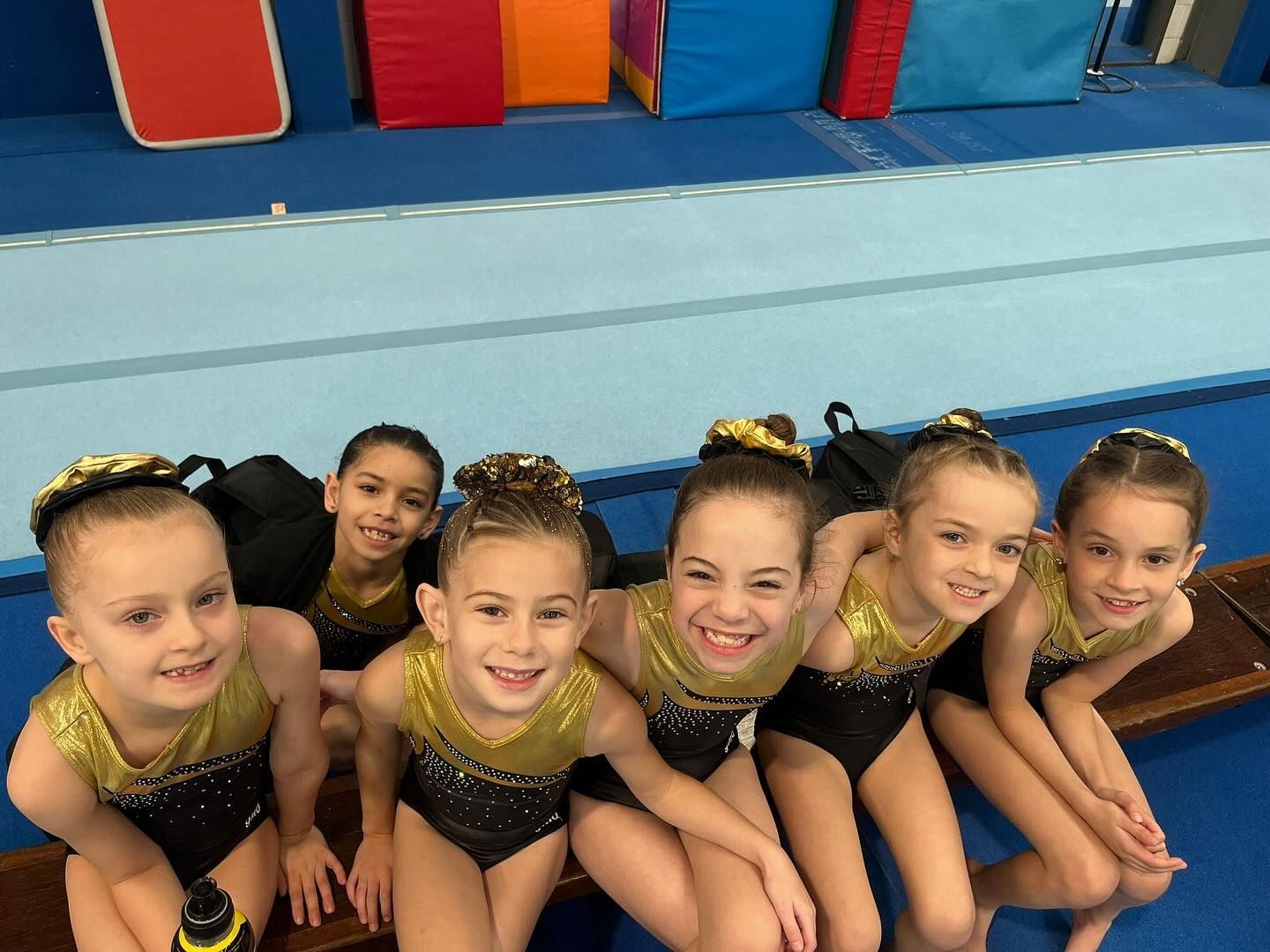 Young Girls Are Jumping In The Air In Front Of A Gold Medal Gymnastics Logo — Gold Medal Gymnastics In Molendinar, QLD