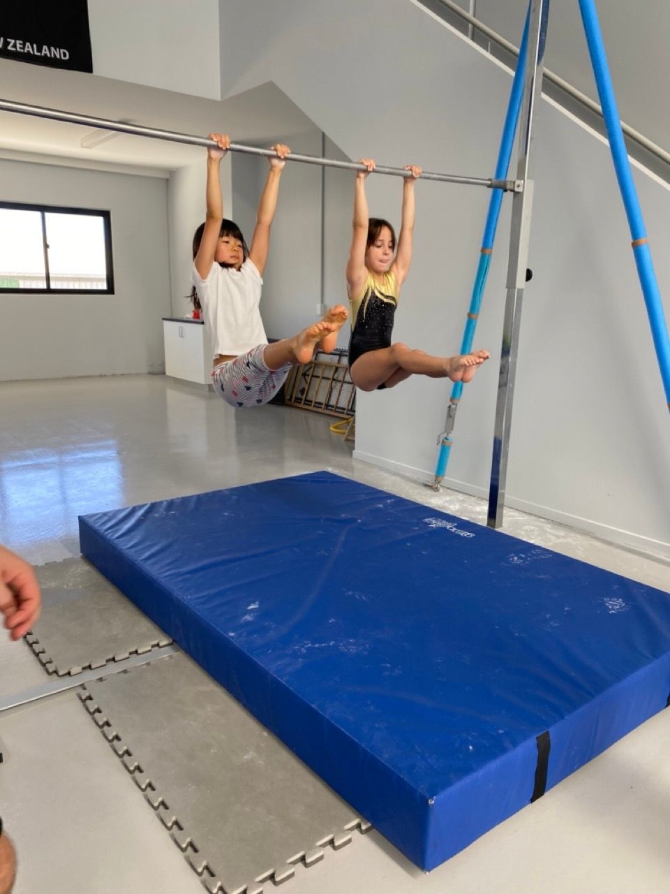 A Boy And A Girl Are Hanging From A Bar In A Gym — Gold Medal Gymnastics In Molendinar, QLD