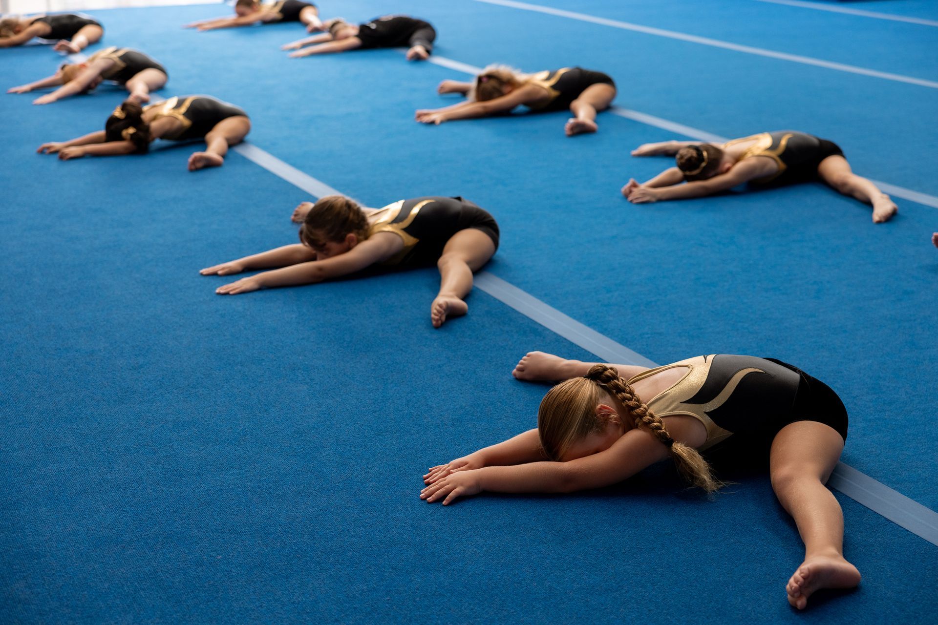 A Group of Young Girls Are Doing Exercises on a Blue Mat in a Gym — Gold Medal Gymnastics In Molendinar, QLD