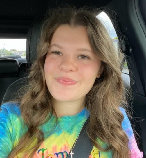 Woman with wavy brown hair, wearing a tie-dye shirt, smiling in a car — Gold Medal Gymnastics In Molendinar, QLD