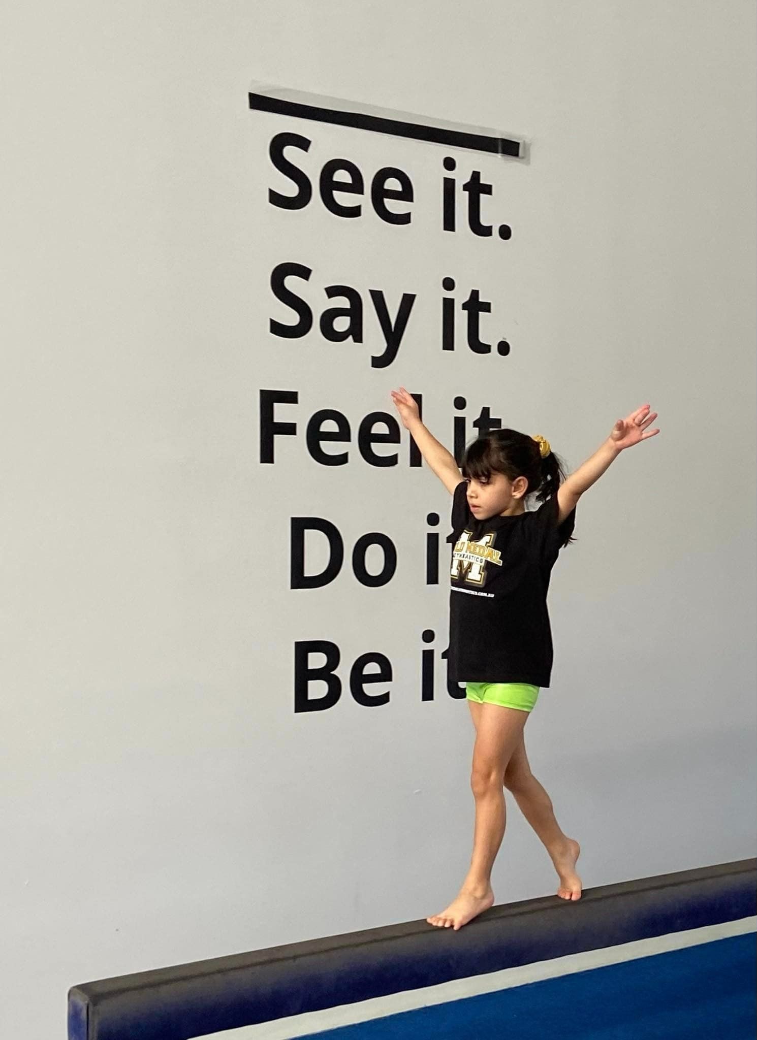 A Little Girl Balances On A Balance Beam In Front Of A Wall — Gold Medal Gymnastics In Molendinar, QLD