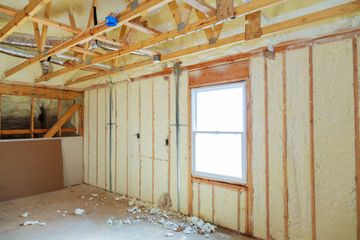 Unfinished room with exposed wooden framing, insulation, and a window during construction.