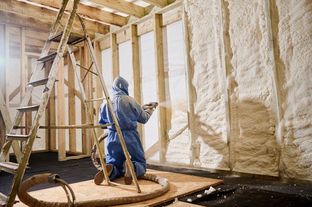 Worker spray-insulating attic walls with foam in an unfinished house