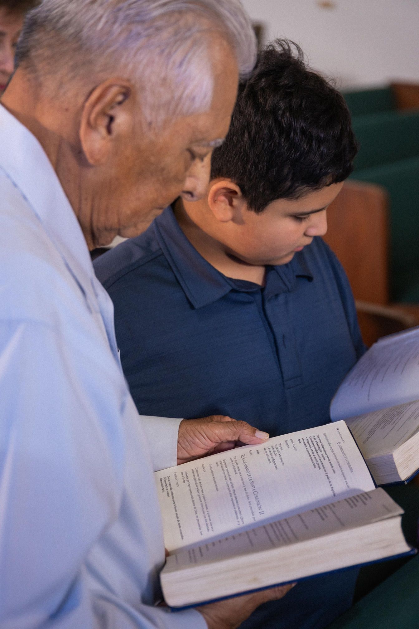 An older man and a young boy read the bible together, both with their own copies.