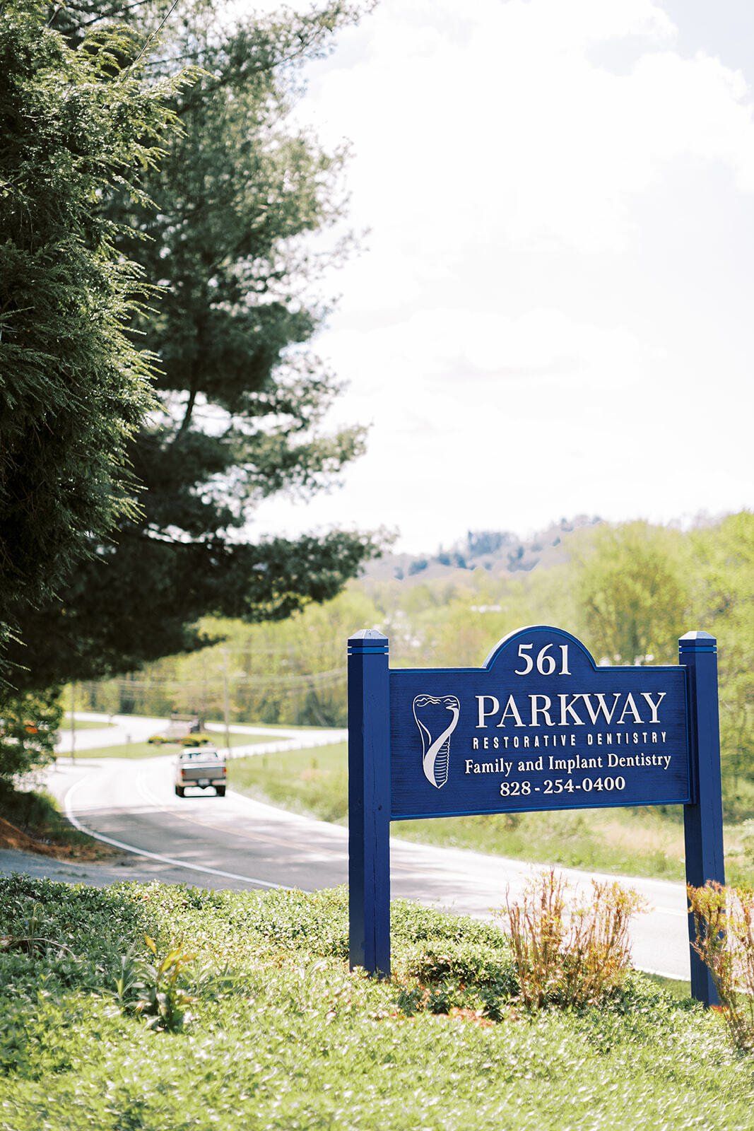 A blue sign is sitting on the side of a road.