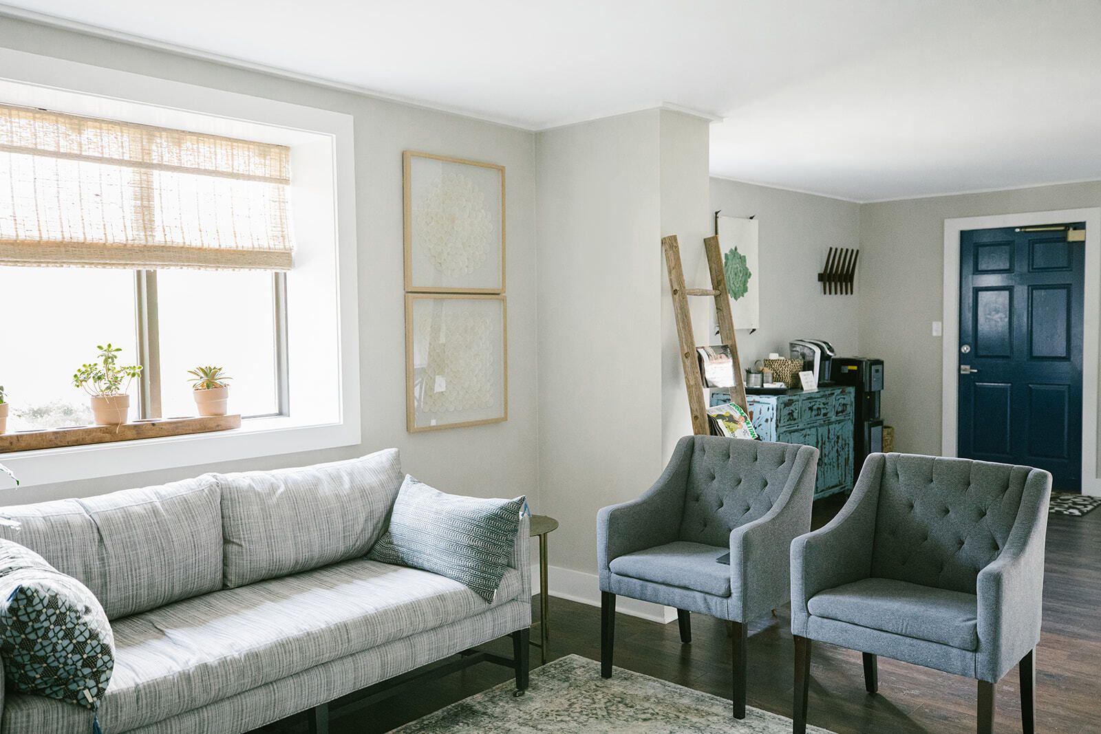 A living room with a couch and chairs and a blue door.