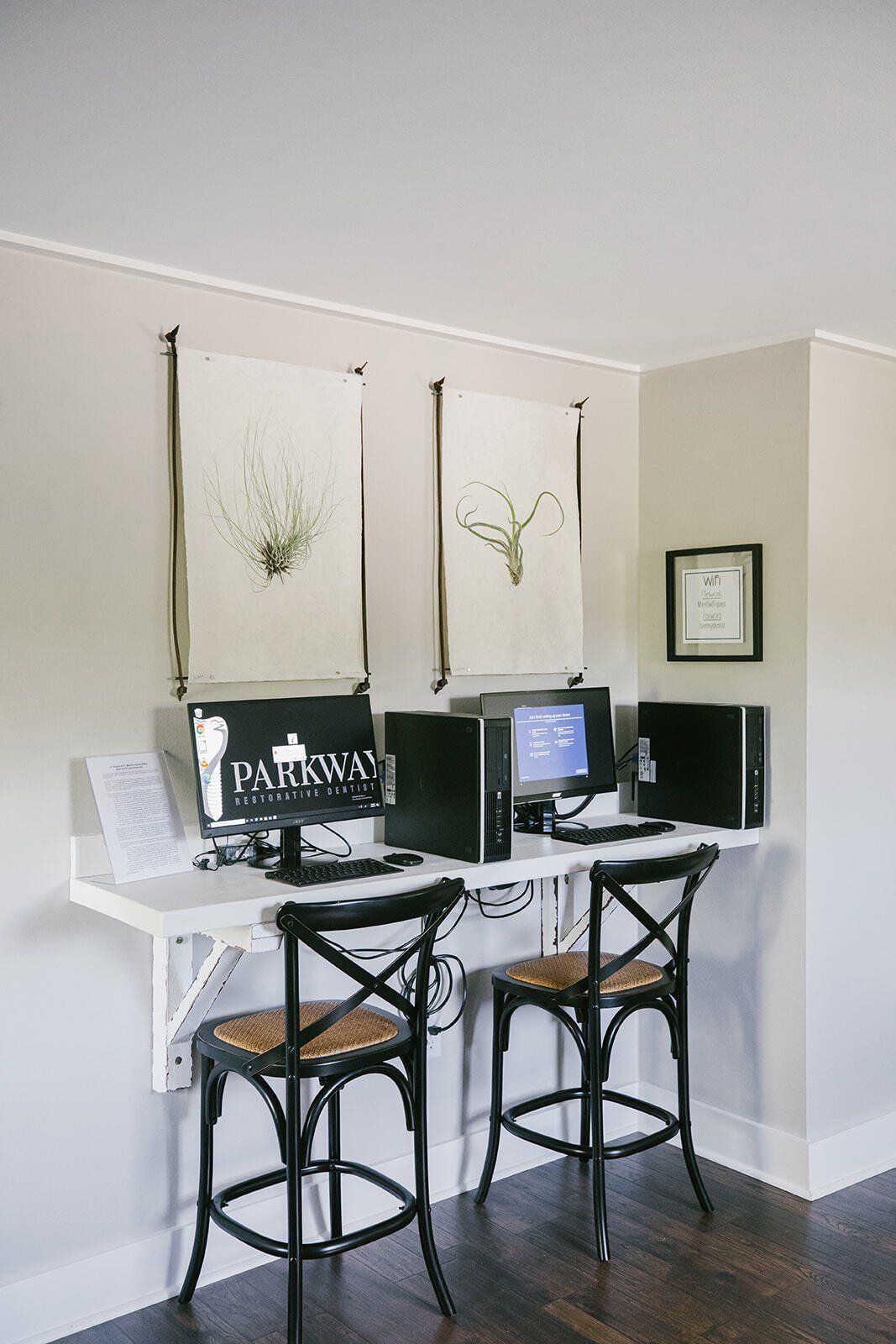 Two chairs are sitting at a desk with two computers on it.