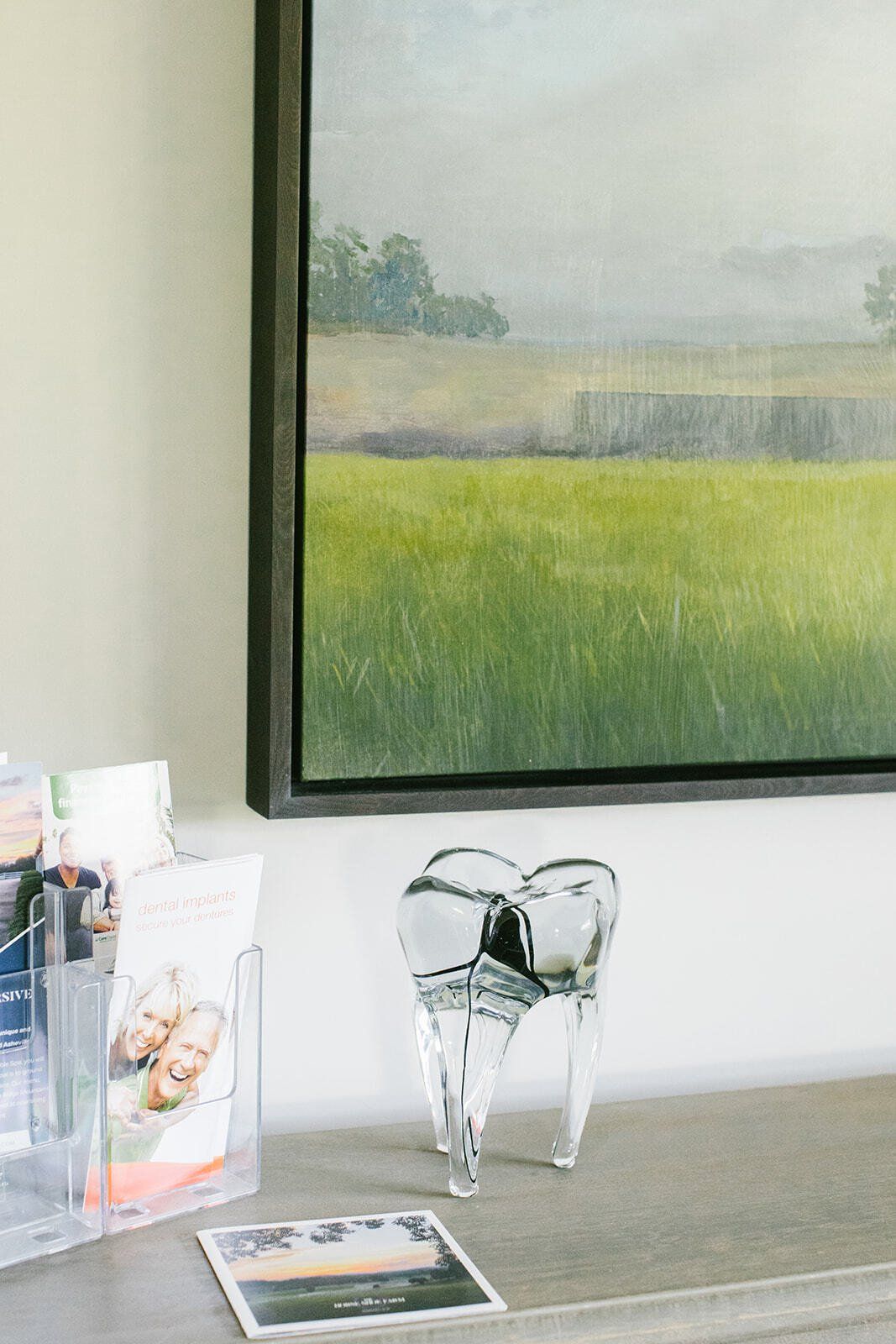 A tooth statue is sitting on a table next to a painting of a field.