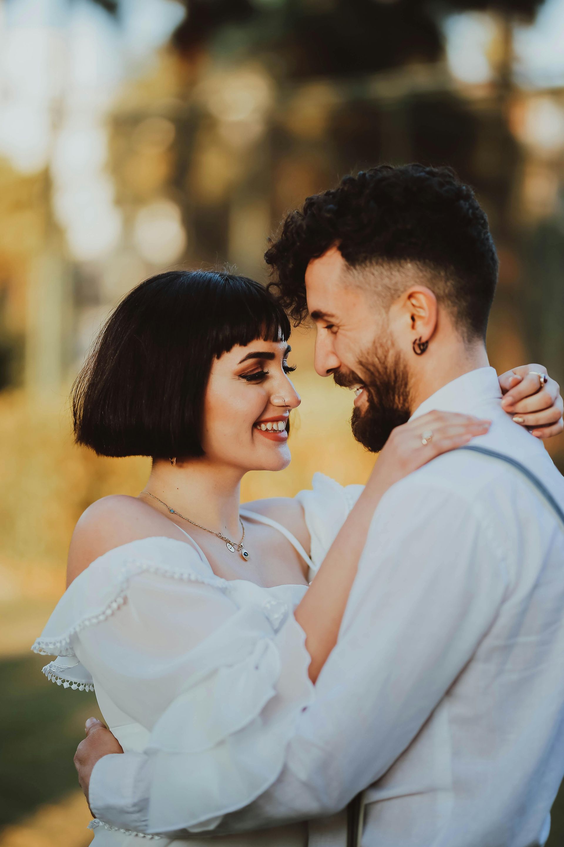 Smiling couple embracing outdoors at sunset, with soft blurred lights in the background