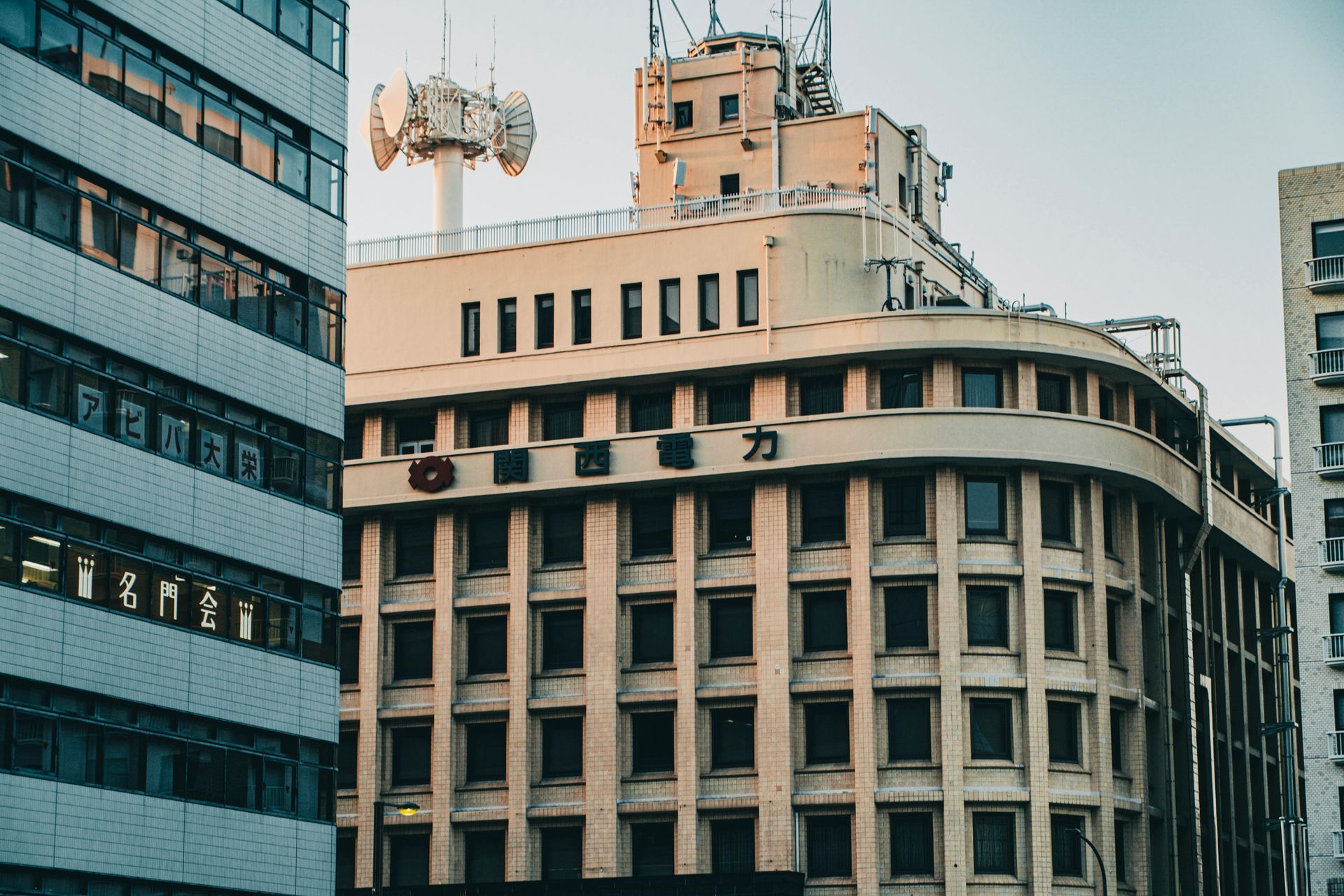 Urban buildings with a curved beige facade beside a modern glass office tower